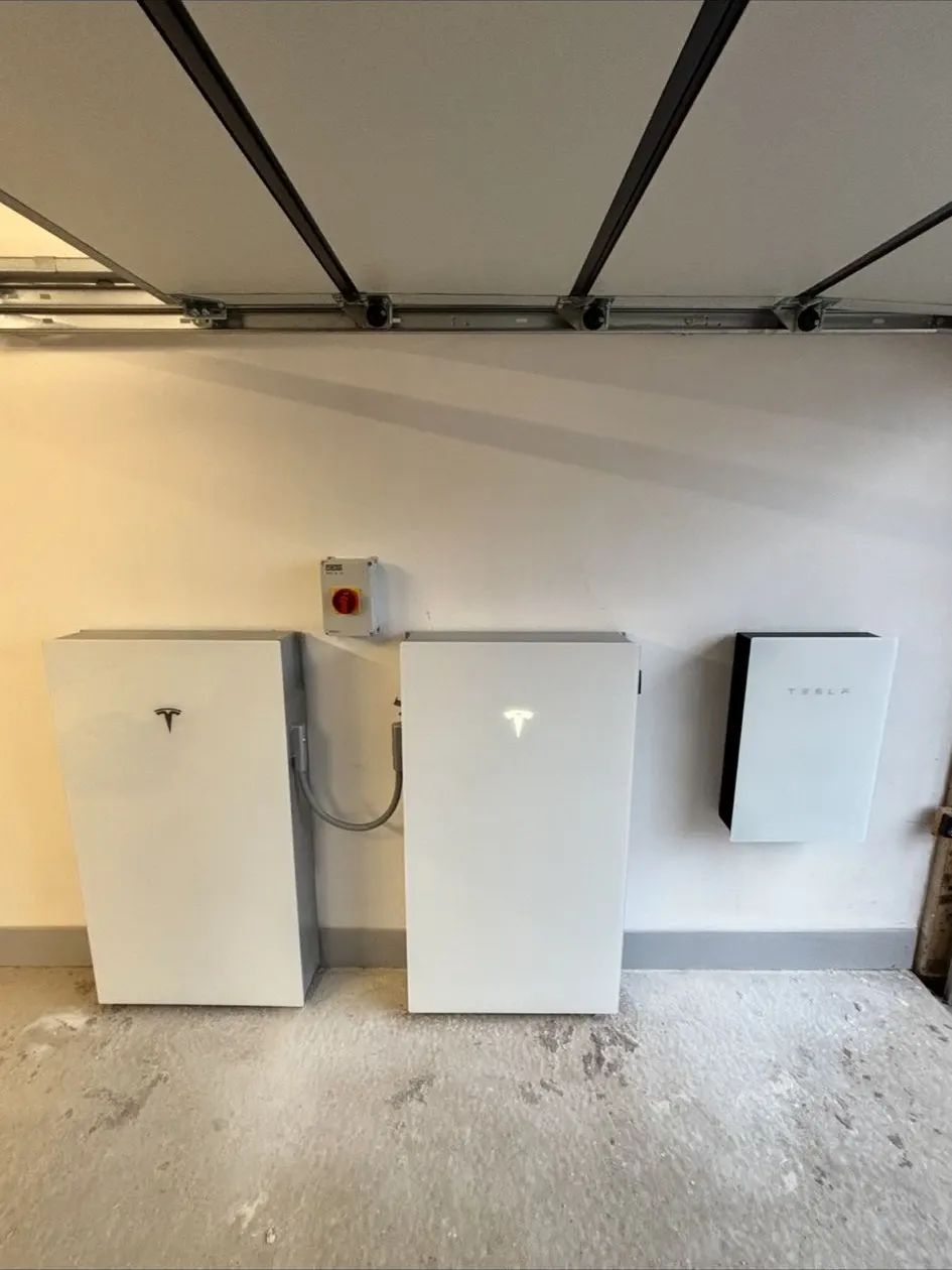 Three Tesla Powerwalls with Backup Gateway in a garage